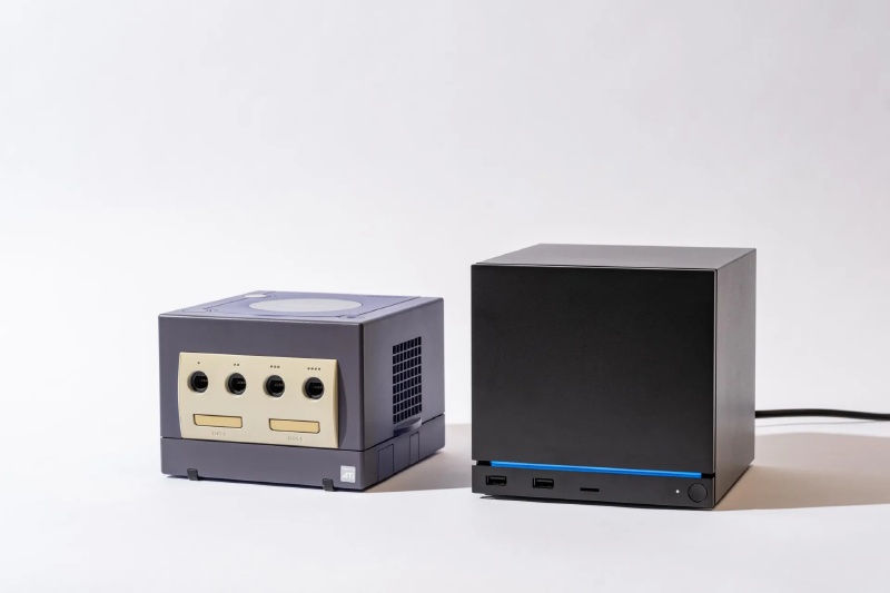A Steam Machine sitting next to a purple Nintendo Gamecube to compare the sizes